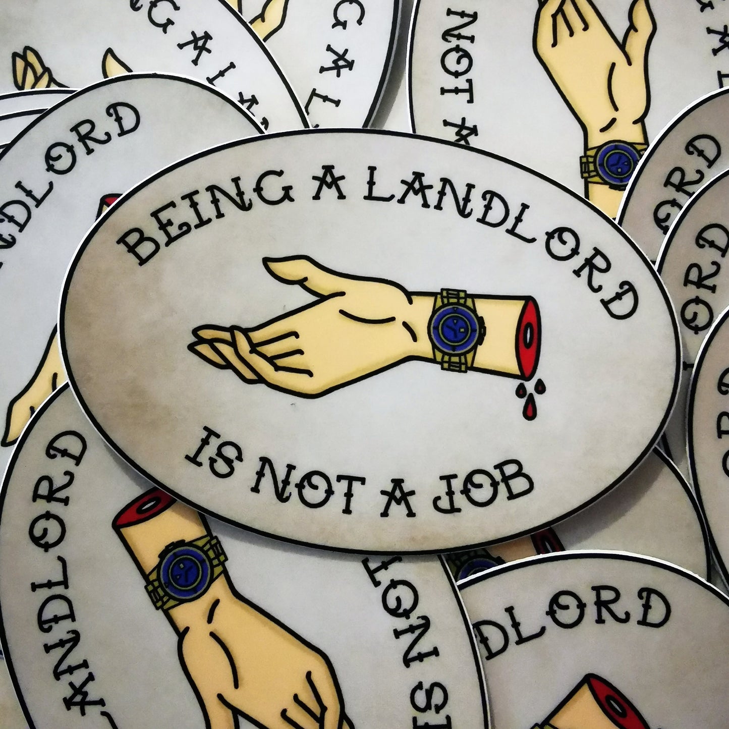 oval sticker with an old stained paper kind of background and the words "being a landlord is not a job" in an all-caps traditional tattoo font and a severed hand dripping blood outstretched for your rent wearing a fancy gold watch