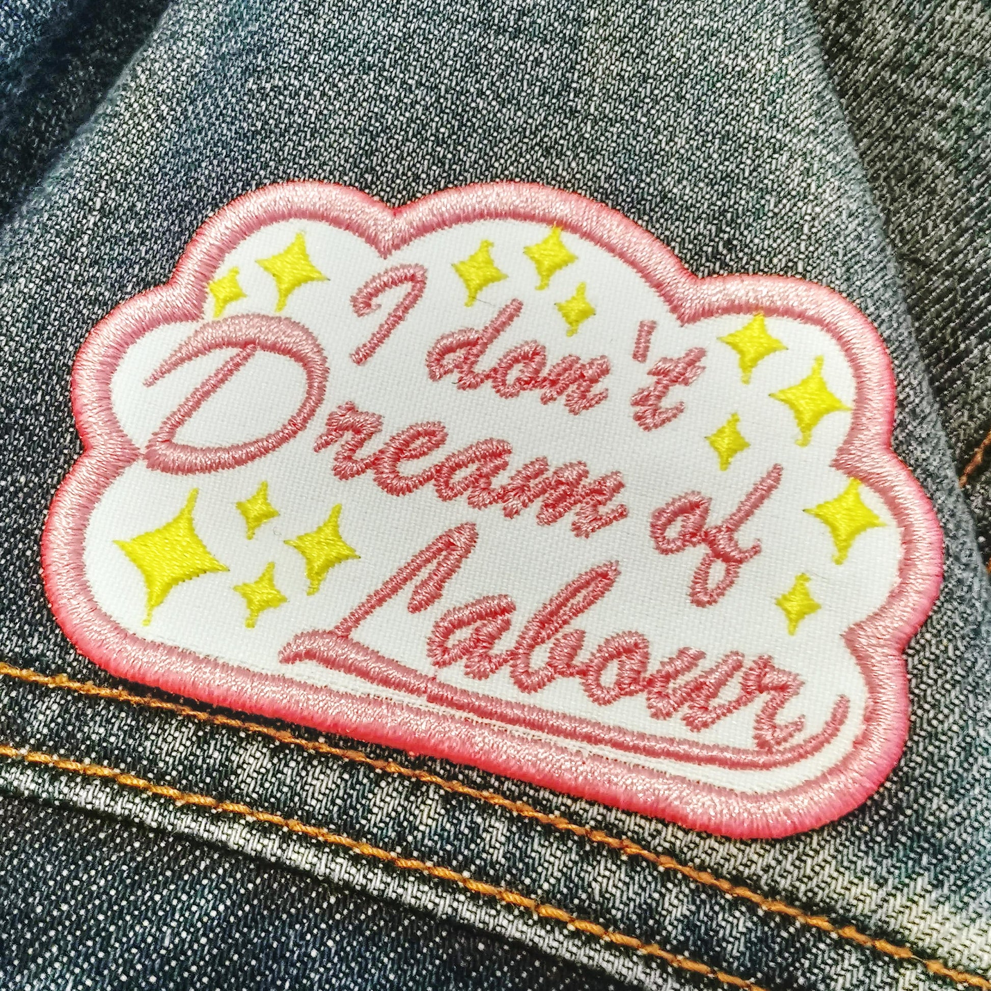 White patch with a cloud that reads "I don't dream of labour"  in pink cursive font with yellow stars