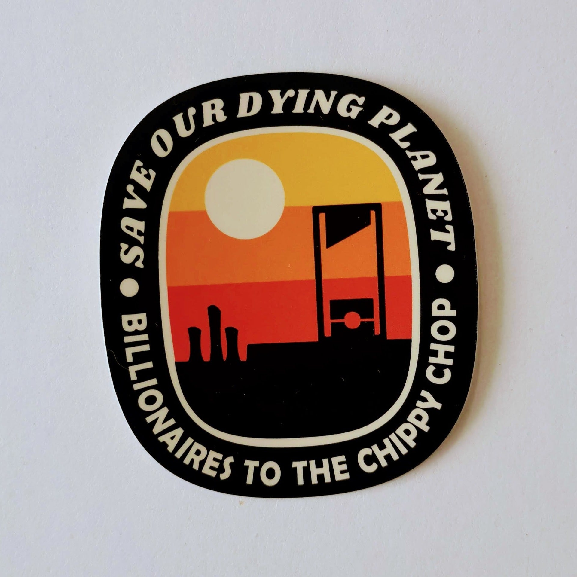 A round-ish rectangle with the words "save our dying planet. billionaires to the chippy chop" around the thick black border and a colour-block sunrise with a certain 18th century french giant slicing machine in the foreground