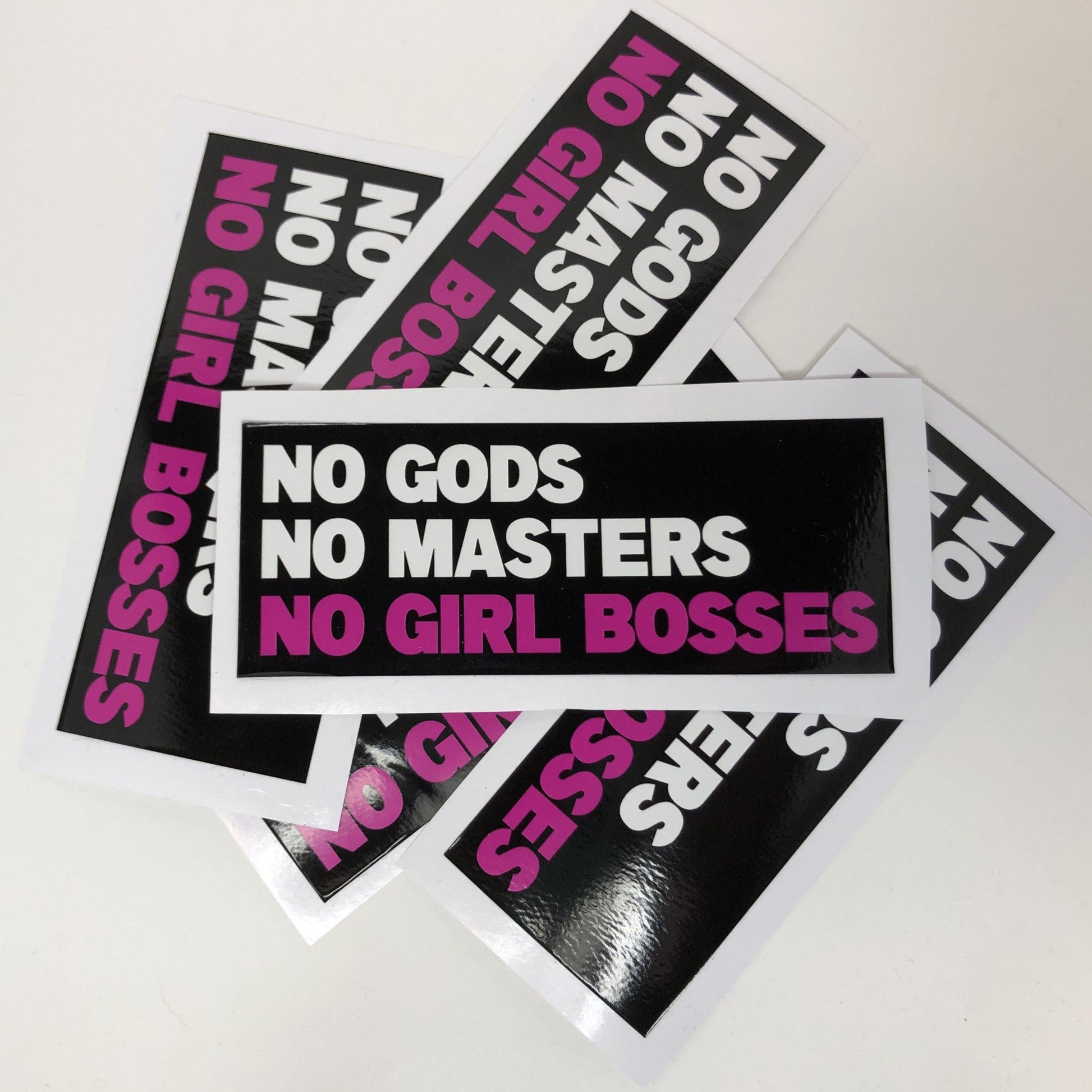 A black rectangle vinyl sticker with the words "no gods no masters" in white and "no girl bosses" in pink